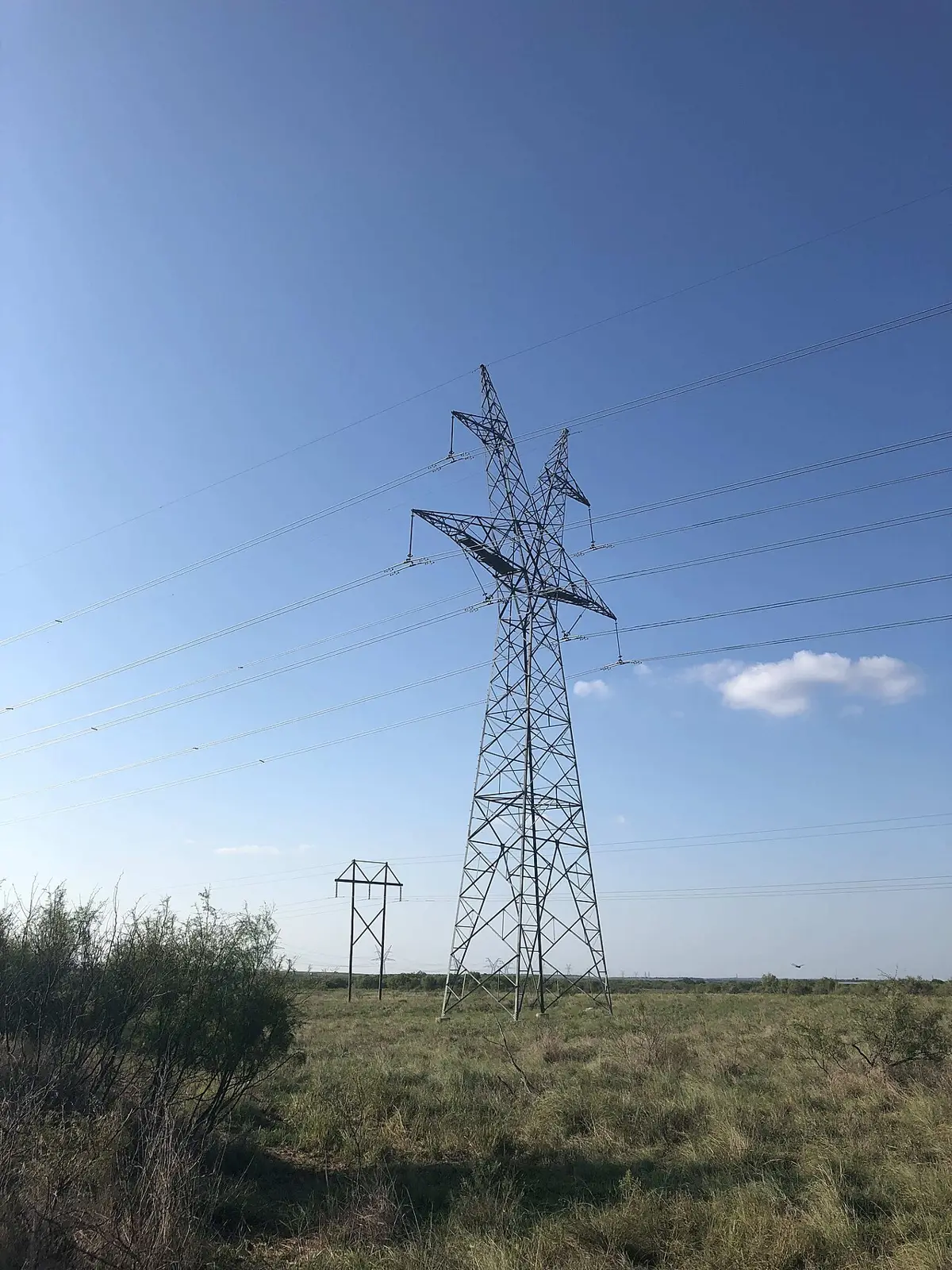 Steel electric transmission tower with lines on open North Texas prairie